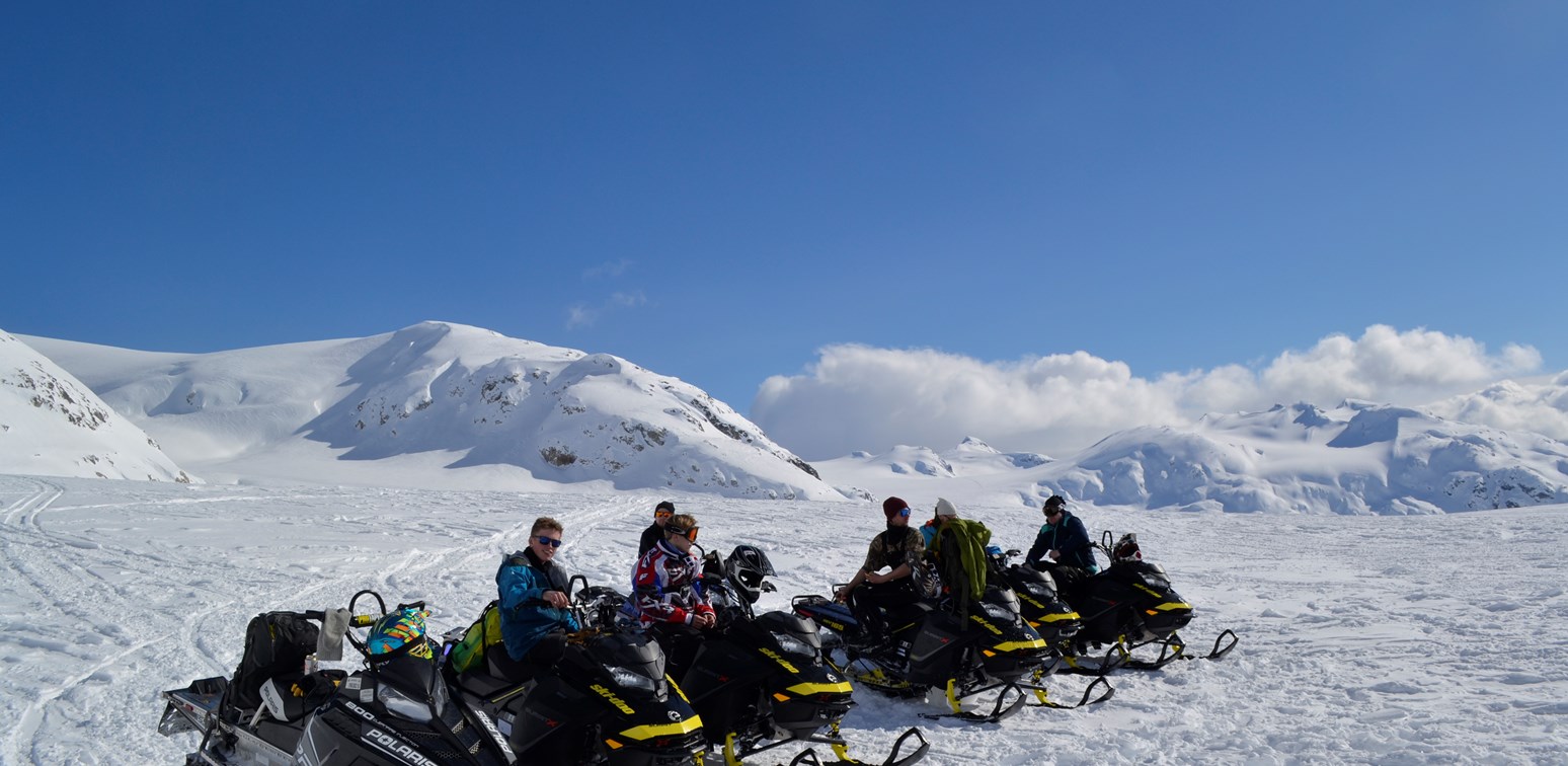 En gruppe snøskuterførere på fjellet.