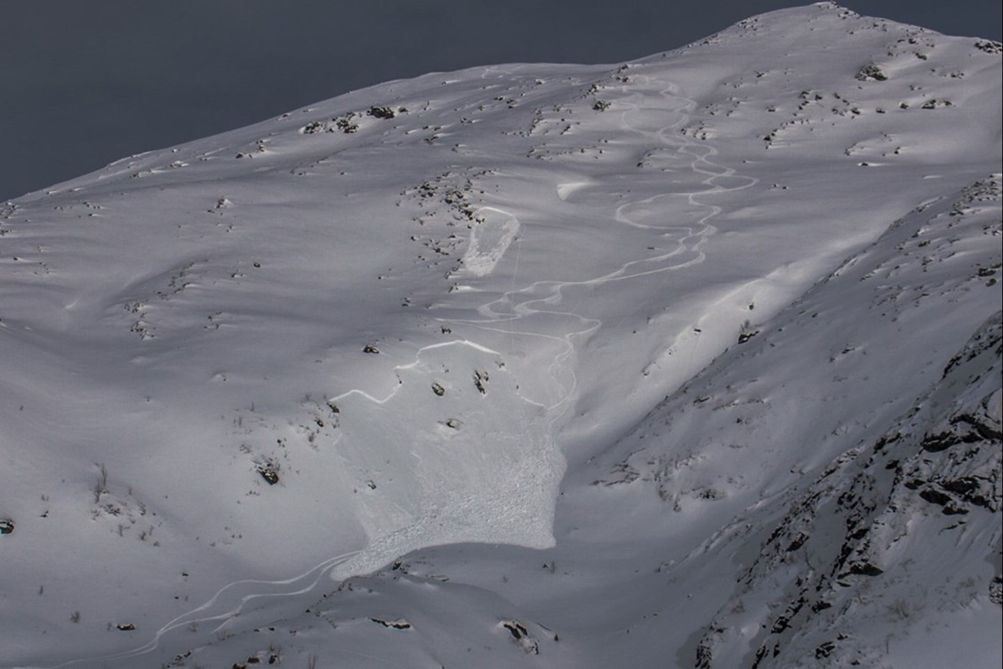 To flakskred som er utløst langs et par skispor som går nedover fjellet.