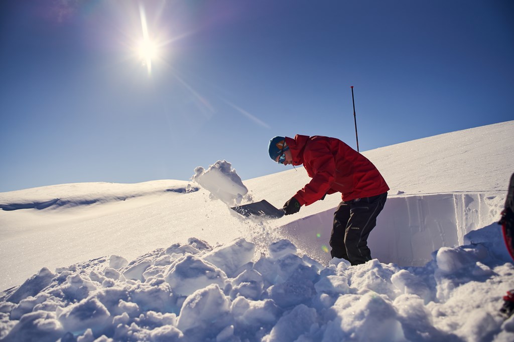 Person graver en snøgrop for å studere snølagene.
