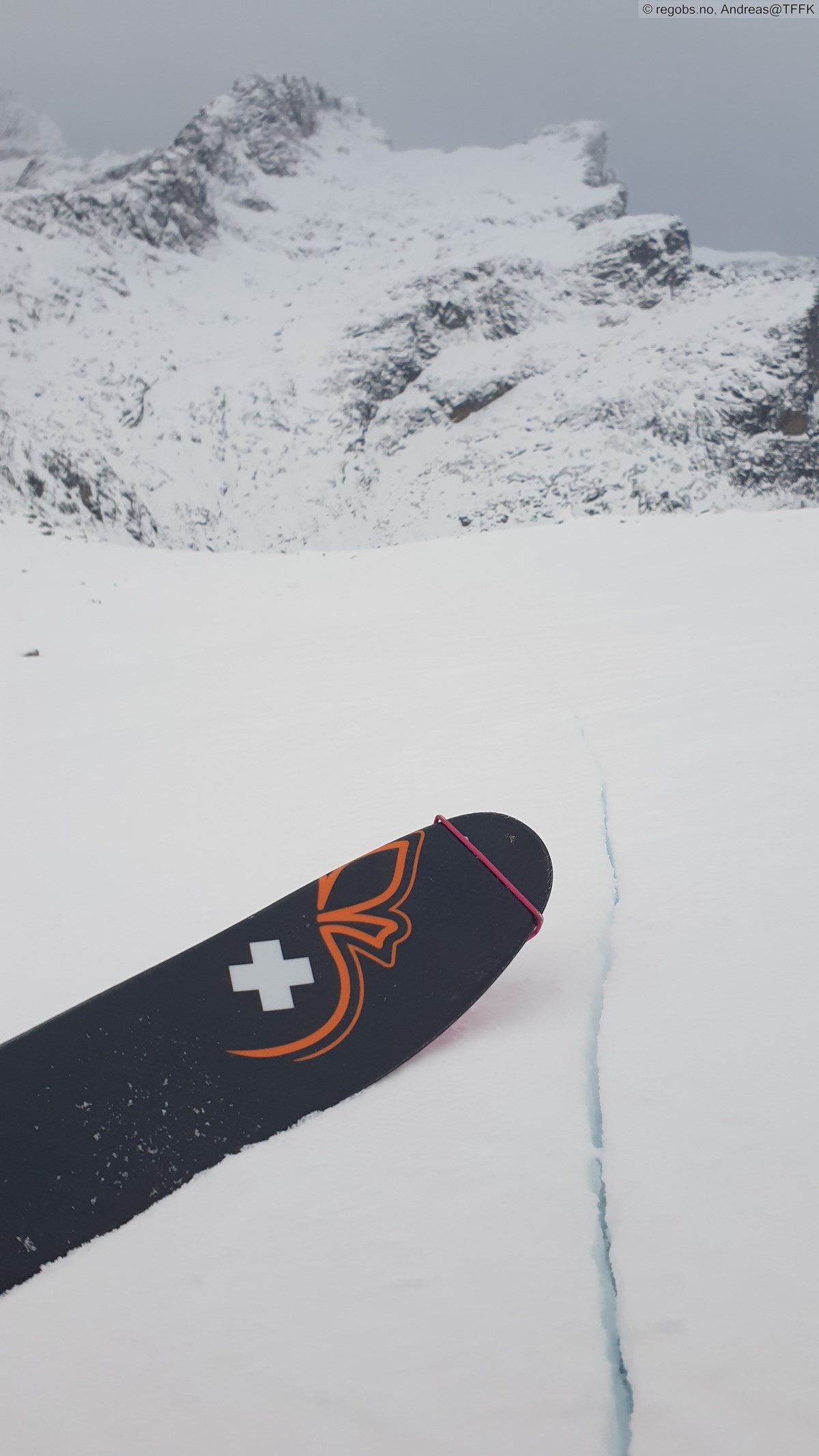 Snødekke med ski og skytende sprekk i snøen.