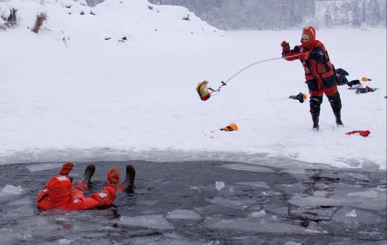 En person som kaster en kasteline til en person som har gått gjennom isen.