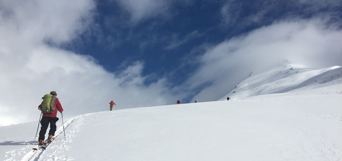 En gruppe skigåere beveger seg oppover en fjellside med god avlastningsavstand.